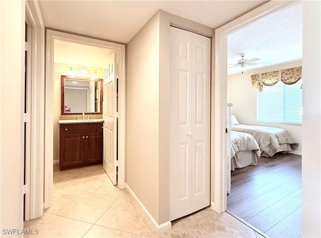 corridor featuring sink, a textured ceiling, and light tile patterned floors