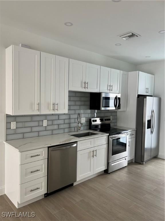 kitchen featuring sink, white cabinets, tasteful backsplash, light hardwood / wood-style floors, and stainless steel appliances