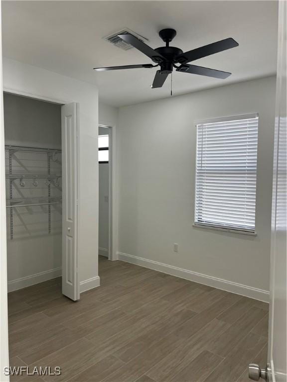 unfurnished bedroom featuring ceiling fan, dark hardwood / wood-style flooring, and a closet