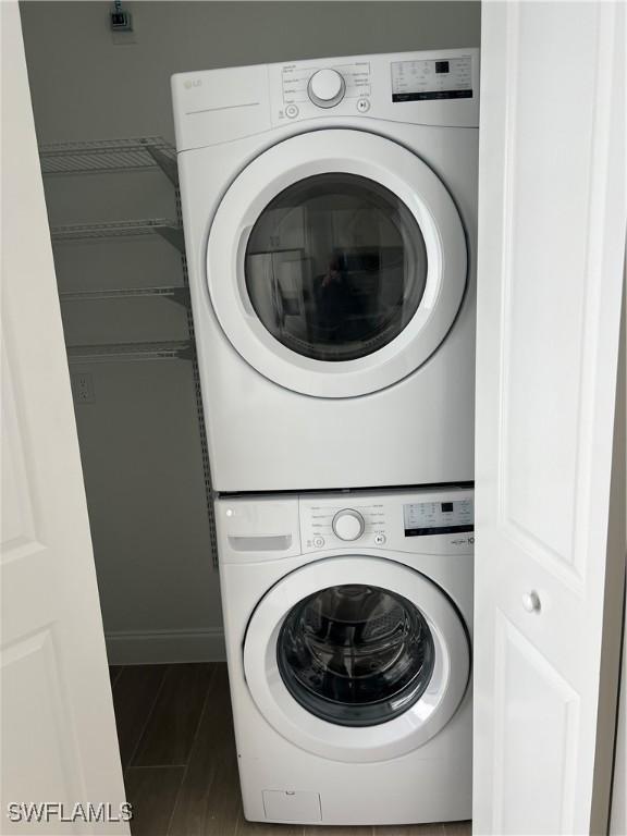 washroom featuring dark wood-type flooring and stacked washer / drying machine