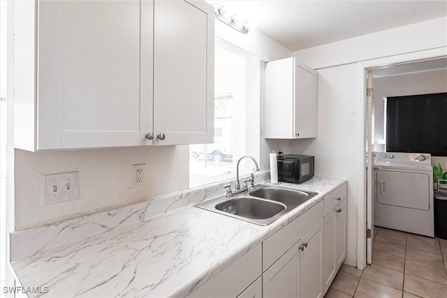 kitchen with sink, washer / dryer, white cabinets, and light tile patterned flooring