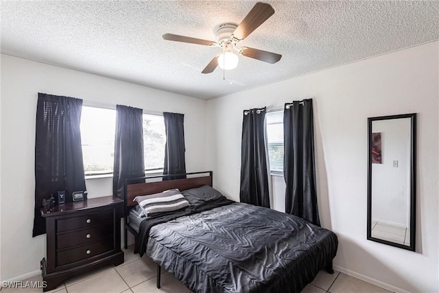 bedroom with a textured ceiling, ceiling fan, and light tile patterned flooring