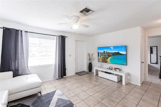 living room featuring ceiling fan, light tile patterned floors, and a textured ceiling