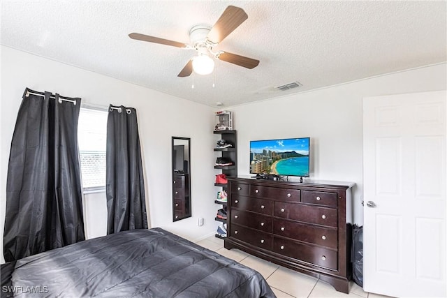 bedroom featuring a textured ceiling, ceiling fan, and light tile patterned flooring