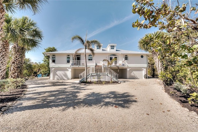 3025 Turtle Gait Ln, Sanibel, FL 33957 - raised beach house with stairway, a porch, an attached garage, and dirt driveway