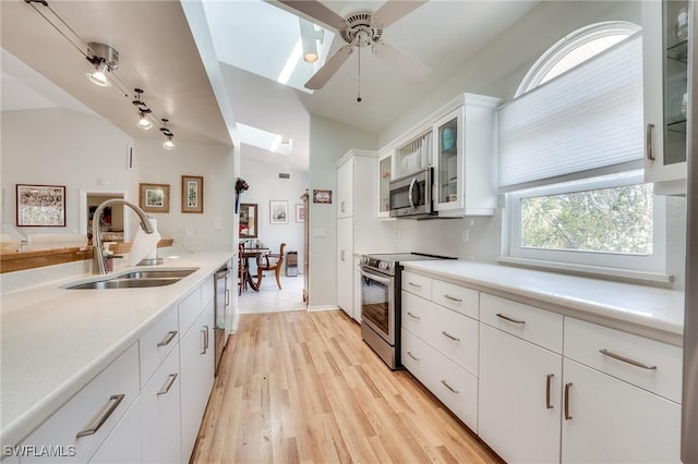 3025 Turtle Gait Ln, Sanibel, FL 33957 - kitchen featuring light wood-style flooring, white cabinets, light countertops, a sink, and stainless steel appliances
