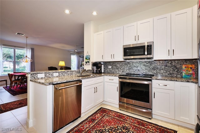 8921 Bristol Bnd, Fort Myers, FL 33908 - kitchen with white cabinets, dark stone counters, kitchen peninsula, and appliances with stainless steel finishes