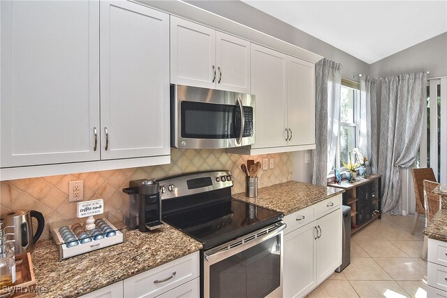 kitchen featuring light tile patterned floors, appliances with stainless steel finishes, tasteful backsplash, white cabinets, and dark stone counters