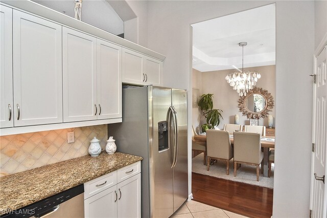 kitchen featuring white cabinetry, light tile patterned floors, dark stone counters, and appliances with stainless steel finishes