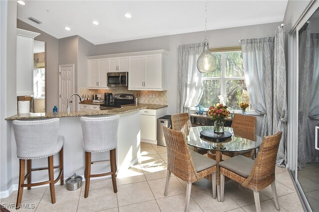 kitchen with stainless steel appliances, white cabinets, stone countertops, decorative backsplash, and kitchen peninsula