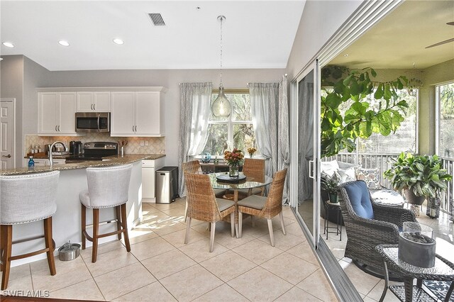 kitchen with white cabinetry, tasteful backsplash, decorative light fixtures, dark stone countertops, and appliances with stainless steel finishes