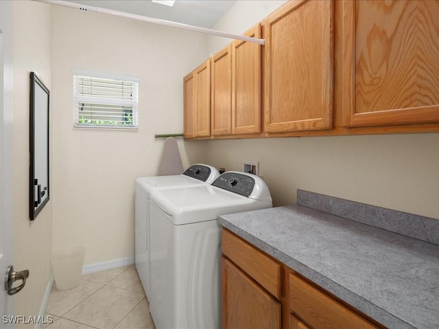 clothes washing area with cabinets, light tile patterned floors, and washing machine and clothes dryer