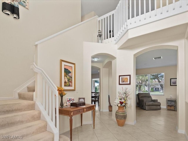 entryway with light tile patterned flooring and a towering ceiling