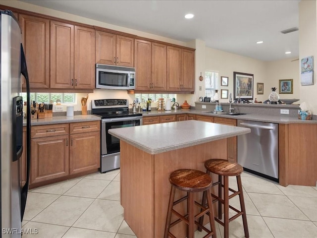 kitchen with a kitchen island, sink, a kitchen breakfast bar, light tile patterned floors, and stainless steel appliances