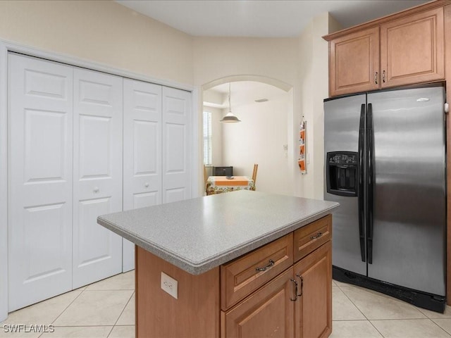 kitchen featuring stainless steel refrigerator with ice dispenser, a kitchen island, and light tile patterned floors