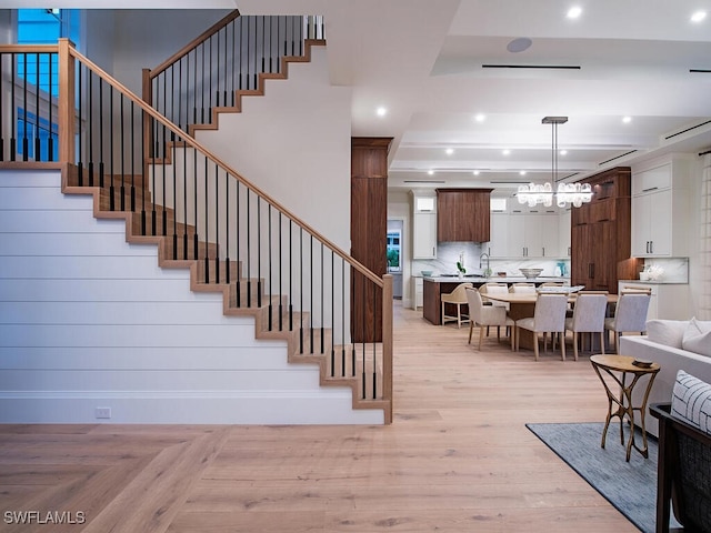 staircase with a tray ceiling, sink, and hardwood / wood-style flooring