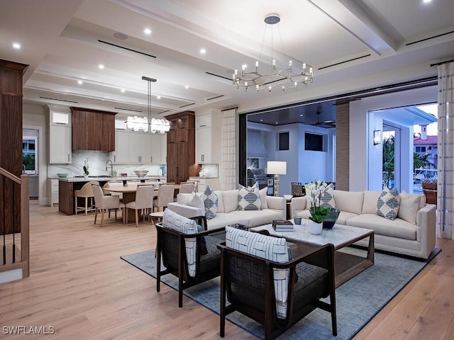 living room featuring beamed ceiling, a chandelier, and light hardwood / wood-style flooring