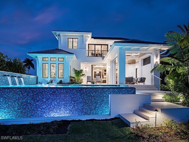 3637 Crayton Rd, Naples, FL 34103 - back of house at twilight with an infinity pool and a balcony