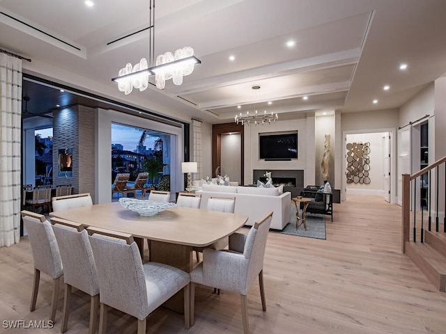 dining room featuring an inviting chandelier, a barn door, and light wood-type flooring