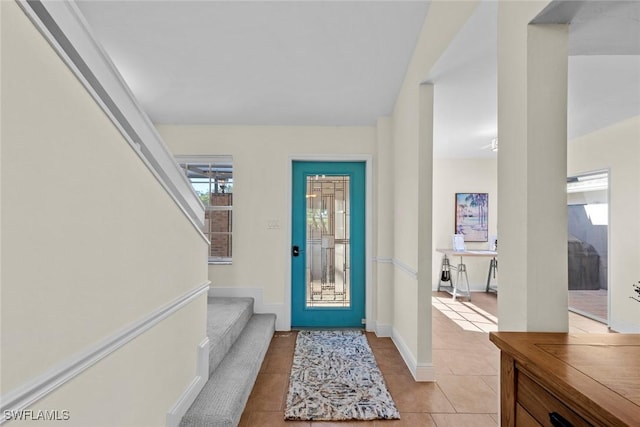 foyer entrance featuring light tile patterned floors, stairs, and baseboards