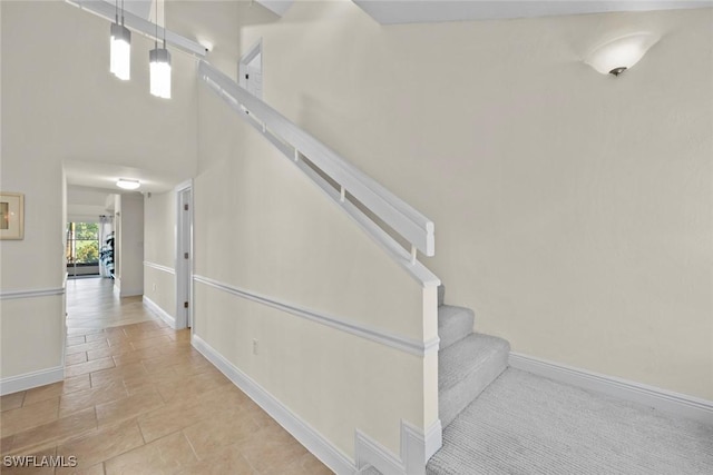 staircase featuring a high ceiling and baseboards