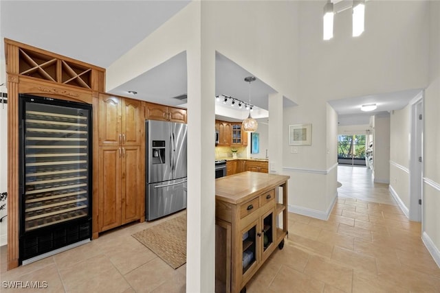 kitchen featuring wine cooler, pendant lighting, stainless steel appliances, and a high ceiling