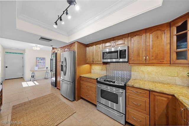 kitchen featuring crown molding, appliances with stainless steel finishes, light stone counters, decorative backsplash, and a raised ceiling