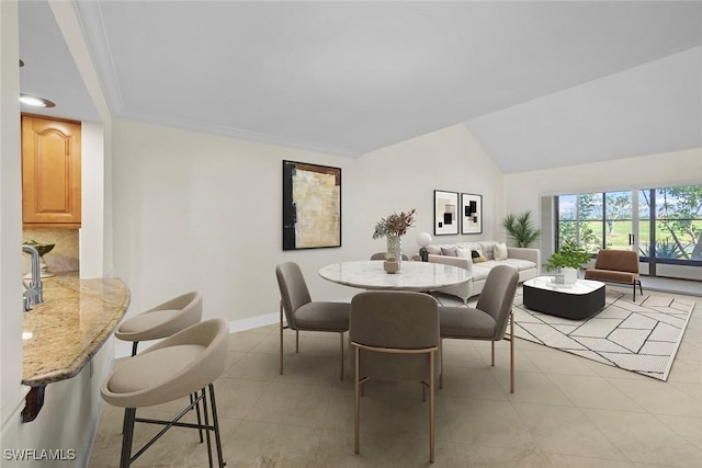 dining area featuring ornamental molding, vaulted ceiling, baseboards, and light tile patterned floors