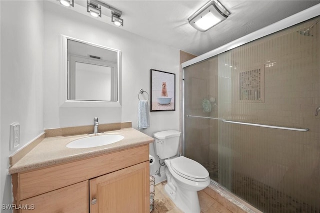 bathroom featuring vanity, an enclosed shower, and toilet