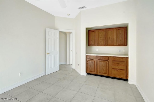 interior space with light tile patterned floors, light countertops, brown cabinets, visible vents, and a ceiling fan