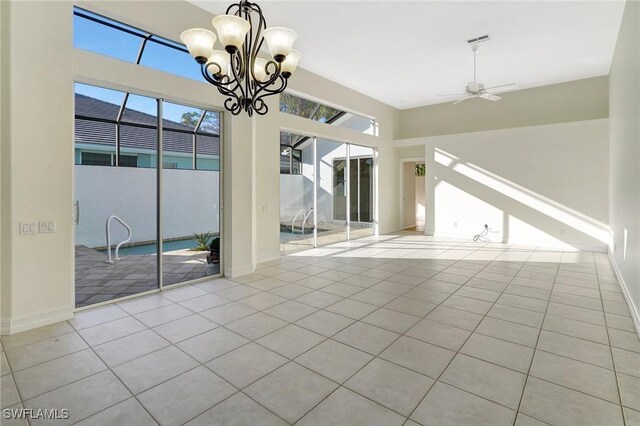 interior space with light tile patterned floors, ceiling fan with notable chandelier, and a healthy amount of sunlight