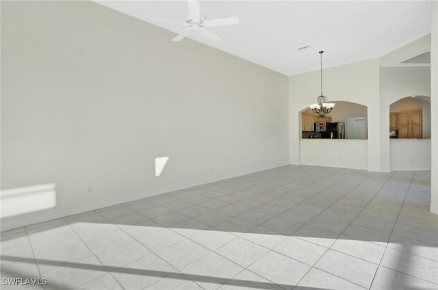 spare room with lofted ceiling, ceiling fan with notable chandelier, and light tile patterned floors