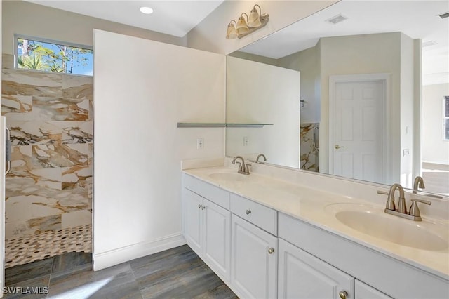 bathroom with hardwood / wood-style flooring, vanity, and a tile shower