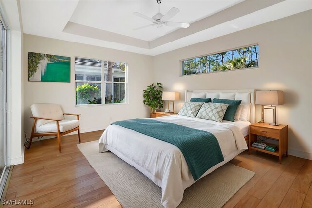 bedroom featuring a tray ceiling, light hardwood / wood-style flooring, and ceiling fan