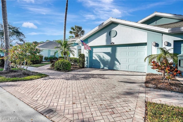 view of side of home with decorative driveway, an attached garage, and stucco siding