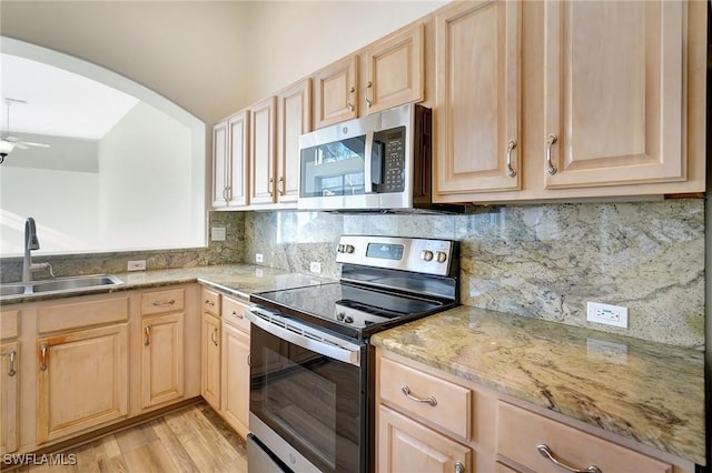 kitchen featuring light brown cabinetry, sink, light hardwood / wood-style flooring, ceiling fan, and stainless steel appliances