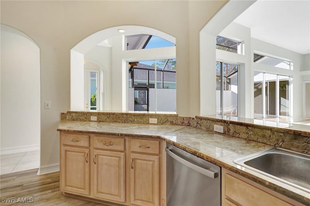 kitchen featuring light wood-type flooring, light brown cabinets, dishwasher, and a sink