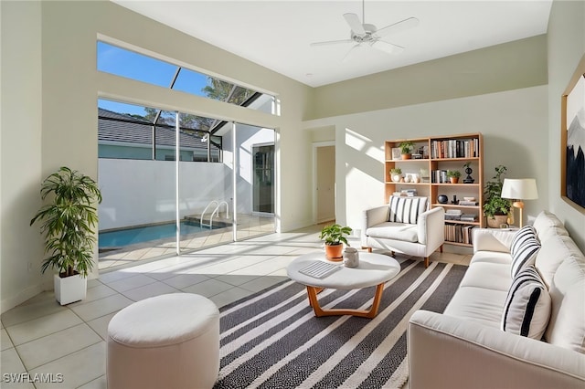 tiled living area featuring a towering ceiling, a ceiling fan, and baseboards