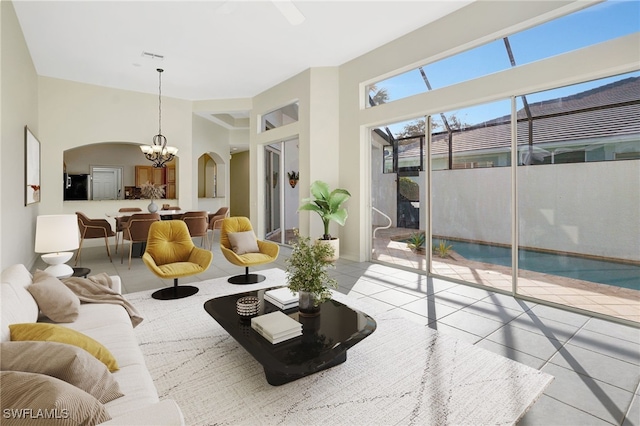 living area with a towering ceiling, arched walkways, an inviting chandelier, and tile patterned floors