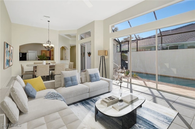 living area with tile patterned floors, a chandelier, and arched walkways