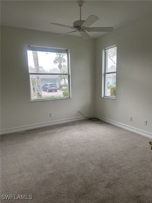 carpeted spare room featuring a ceiling fan, baseboards, and a healthy amount of sunlight