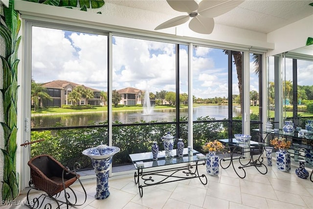 sunroom / solarium featuring a water view and ceiling fan