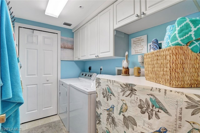 washroom featuring cabinets, light tile patterned floors, and washer and clothes dryer