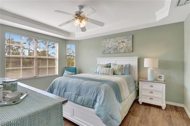 bedroom featuring hardwood / wood-style flooring, ornamental molding, a raised ceiling, and ceiling fan