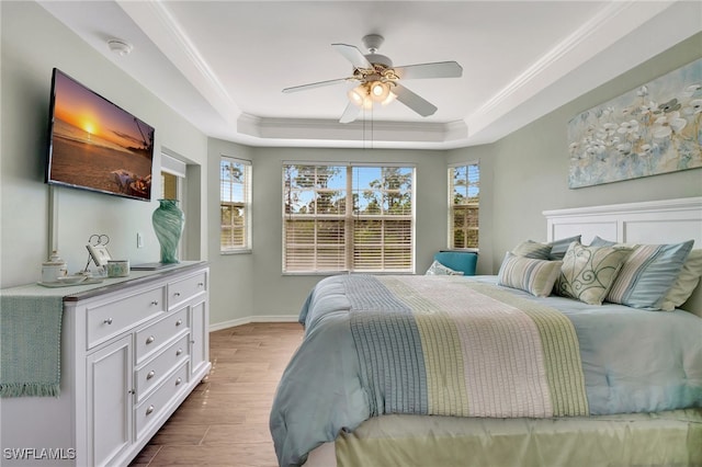 bedroom featuring ceiling fan, ornamental molding, a tray ceiling, and light hardwood / wood-style flooring