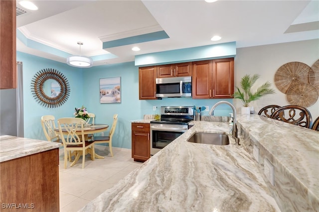 kitchen with pendant lighting, a raised ceiling, sink, stainless steel appliances, and light stone countertops