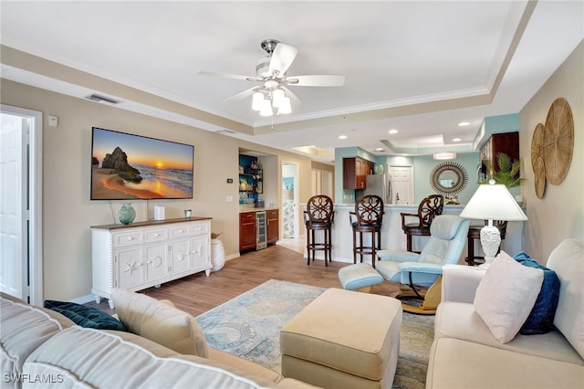 living room with wine cooler, light hardwood / wood-style floors, a raised ceiling, and ceiling fan