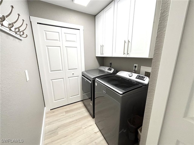 washroom featuring cabinets, washing machine and dryer, and light wood-type flooring