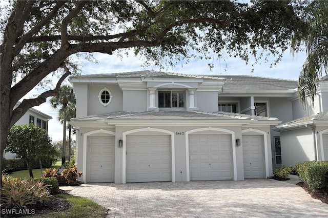 view of front of property with stucco siding, a tile roof, decorative driveway, and a garage