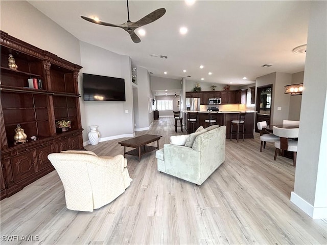 living room featuring vaulted ceiling, light hardwood / wood-style floors, and ceiling fan